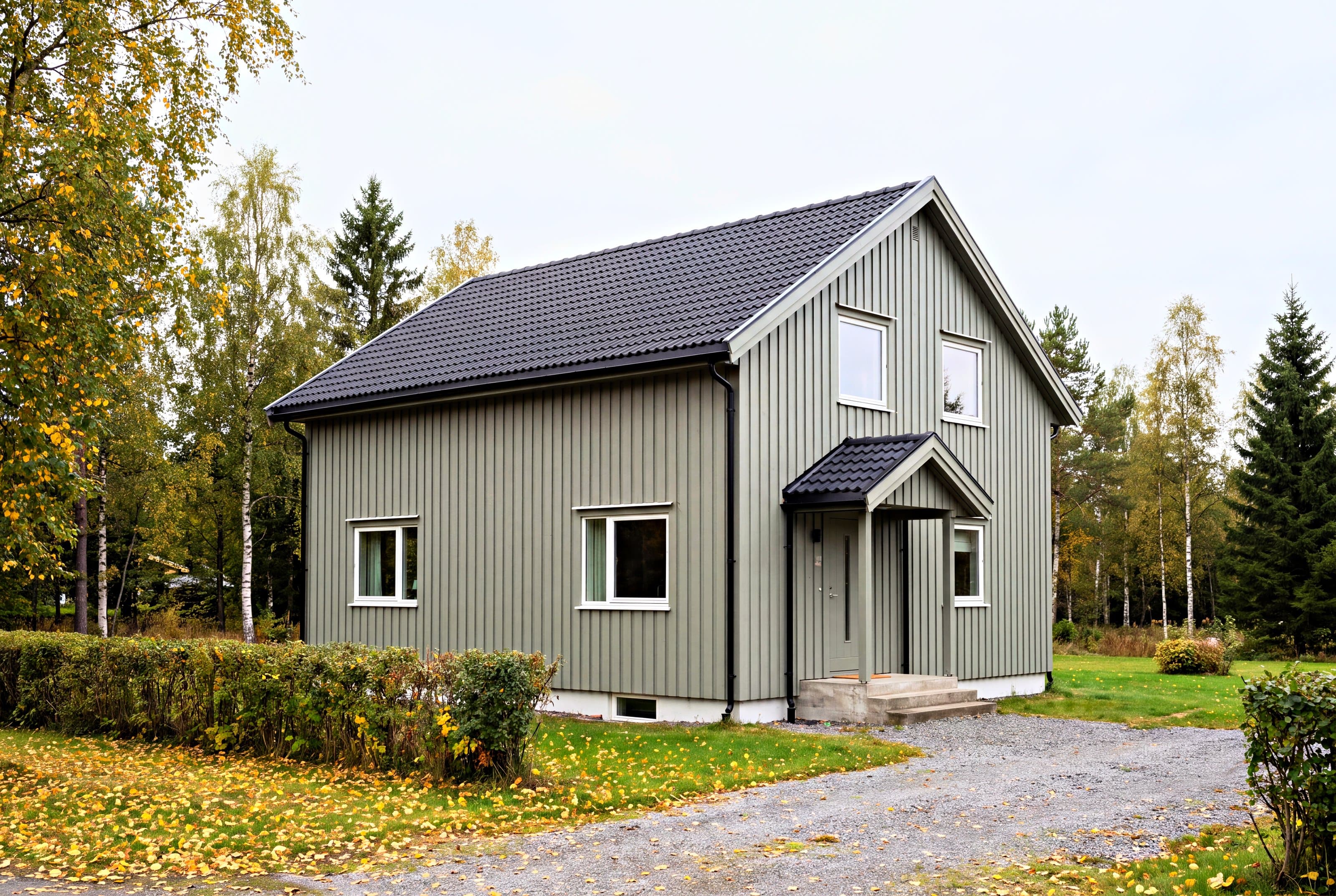 Enebolig med nytt svart takstein-tak og ny grågrønn stående kledning, en grå høstdag.